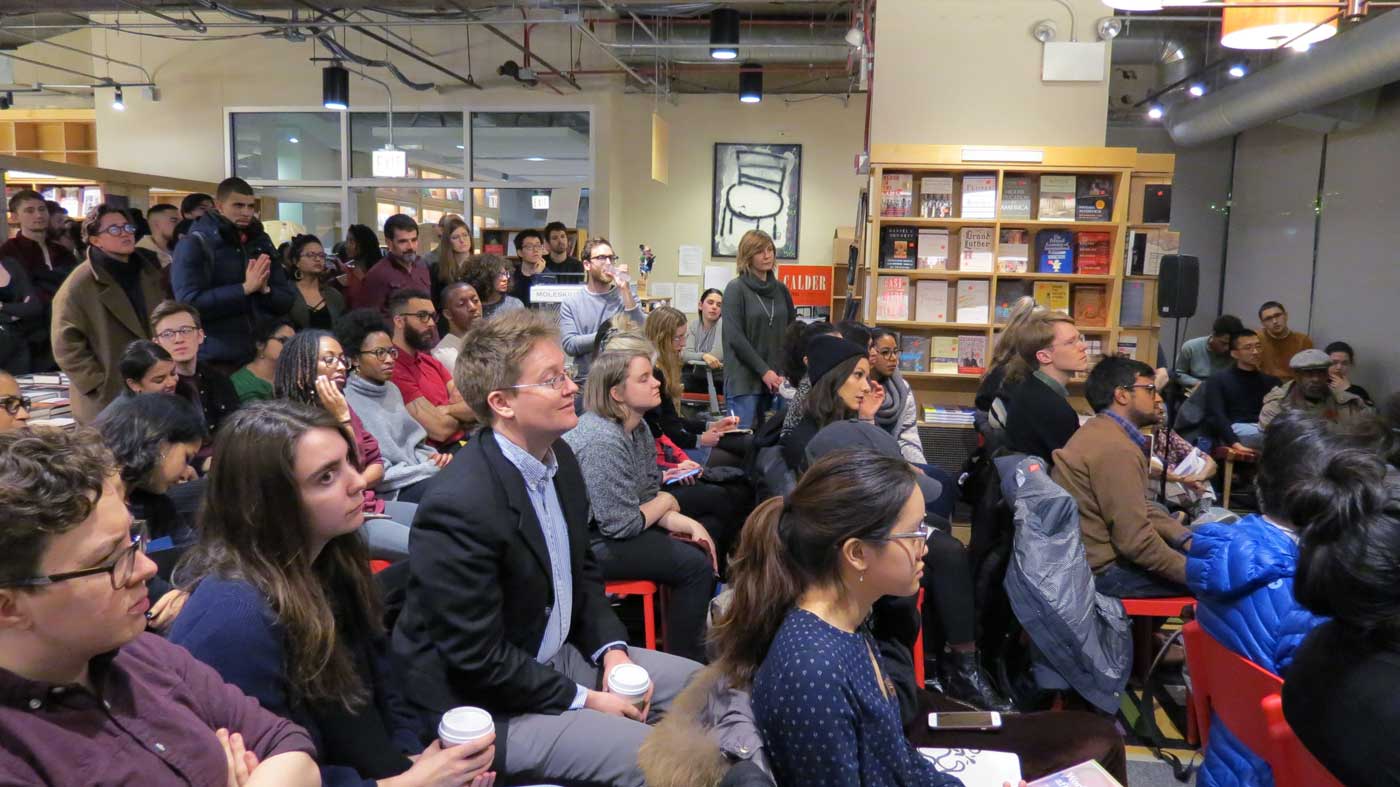 An audience gathers to listen to panelists speak