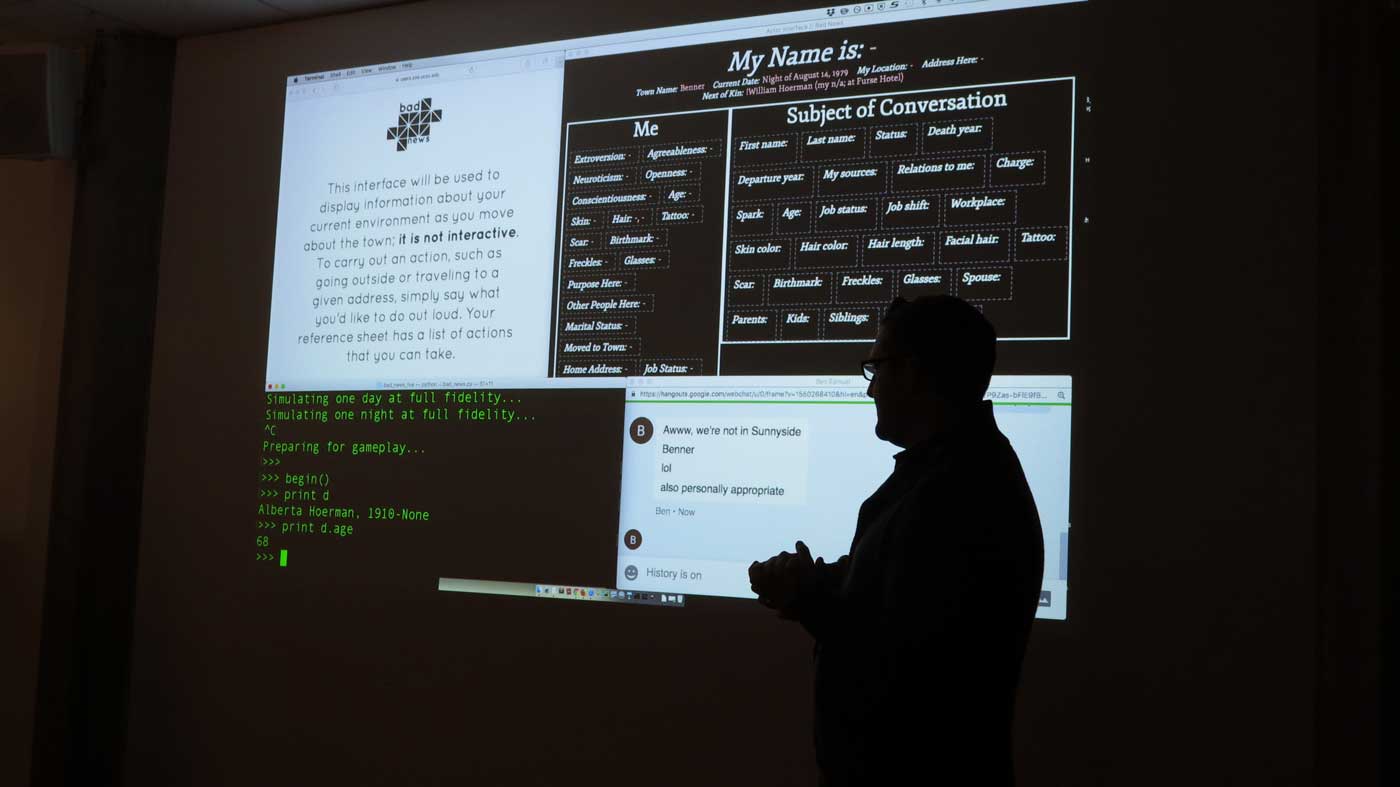 A person stands in front of a screen showing a powerpoint presentation while speaking to an audience