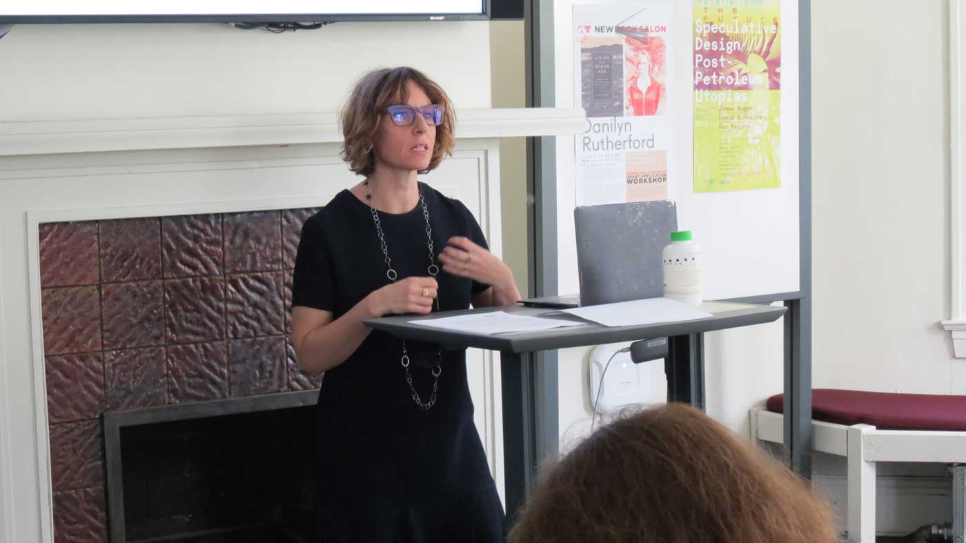 Dorit Geva stands and talks in front of an audience