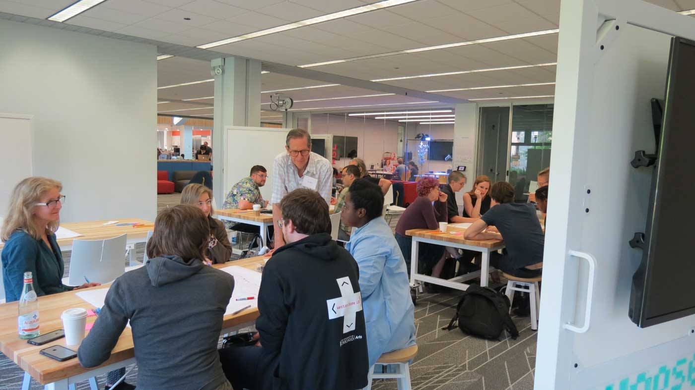 a room with tables where people are sitting and talking