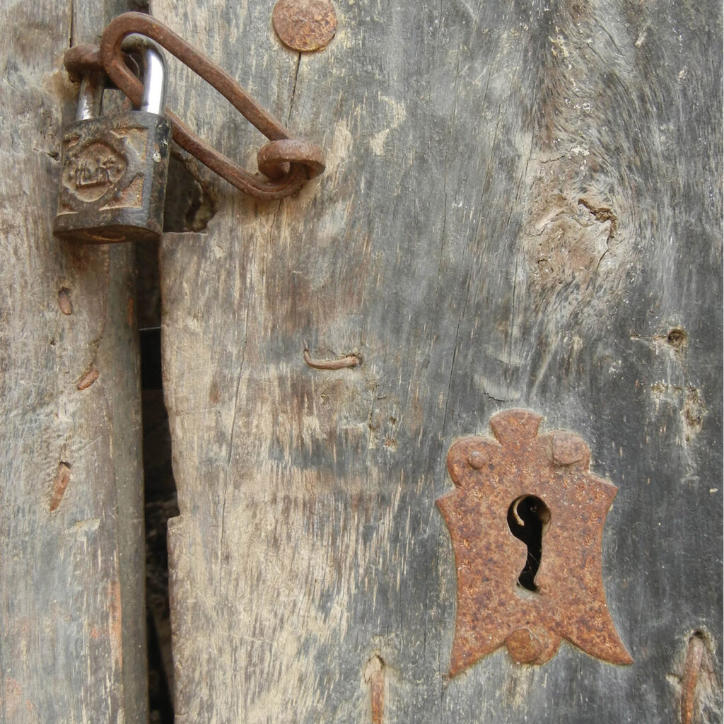 Wooden door with a keyhole and locked by a padlock.