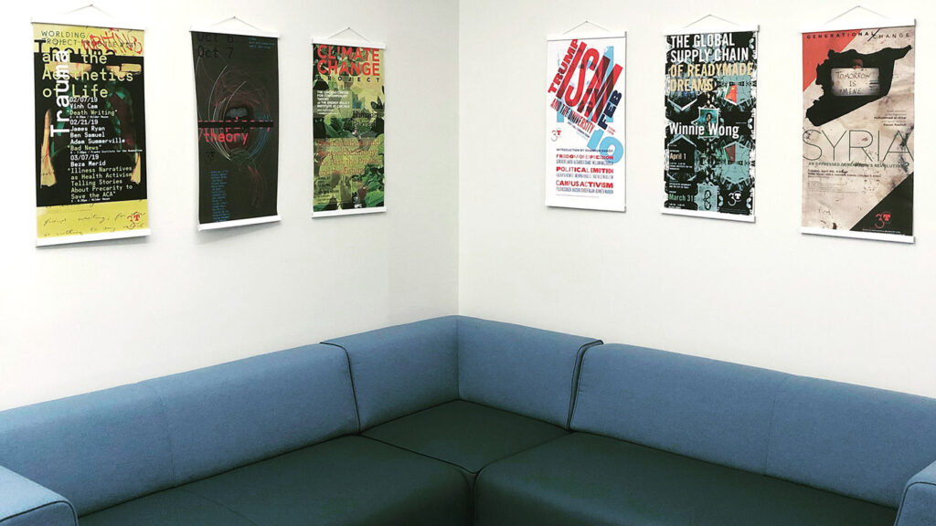 L-shaped blue sofa in corner of room with six posters hanging on the wall behind it