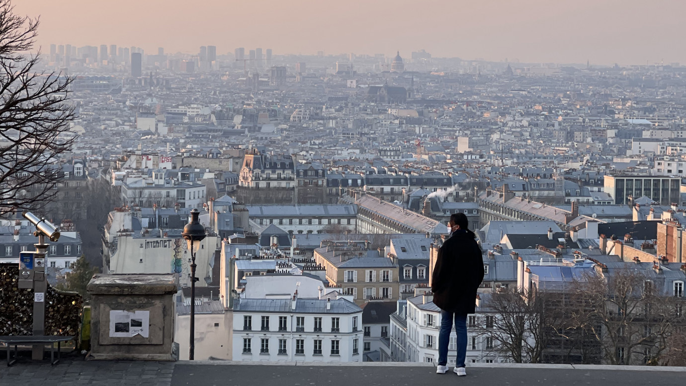 Silhouette of a figure standing above a Paris cityscape