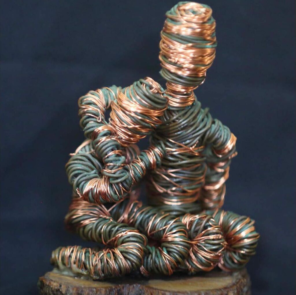 sculpture of two wire figures on a wood base